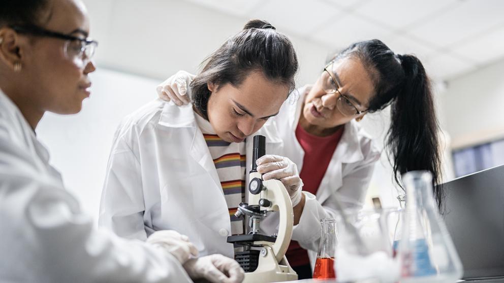 Teachers and students working in science lab with microscope